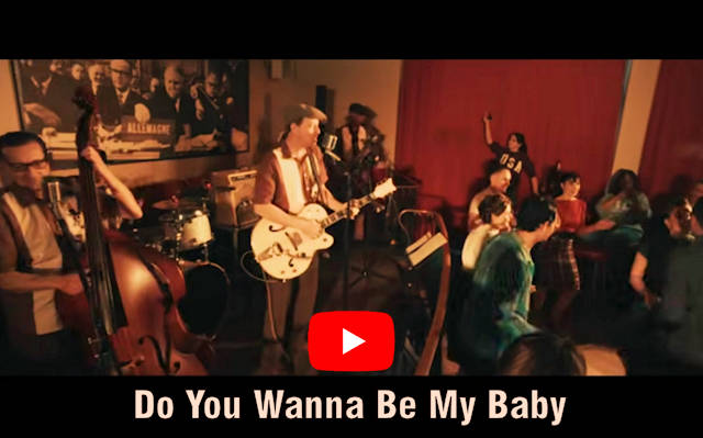 Man sieht Tänzer vor einer Bühne mit band tanzen. Darunter steht der Songtitel "Do You Wanna Be My Baby" mit dem YouTube Logo darüber.